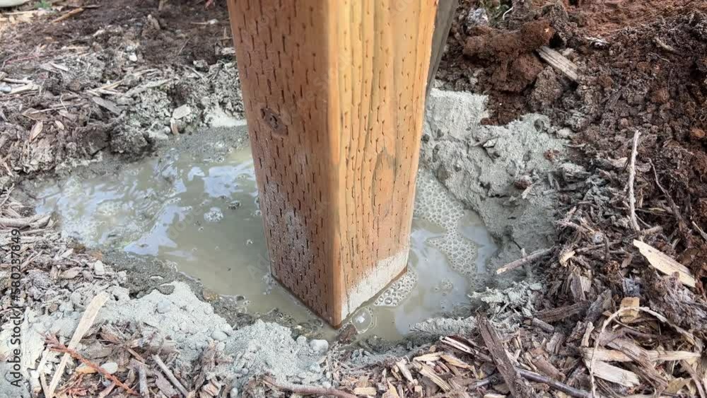 Setting a Level Fence Post Pouring Water on Concrete Built With Treated