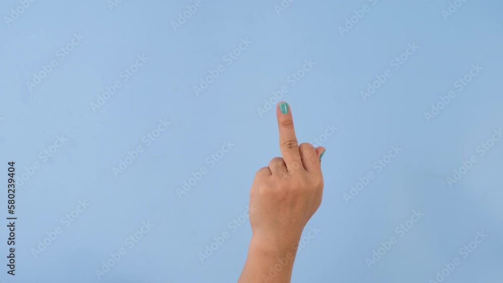 Female hand showing Fuck You middle finger negative sign on pastel blue screen background. Pack of Gestures movements and body language. Female hand showing Fuck You middle finger negative sign on pastel blue screen background. Pack of Gestures movements and body language.