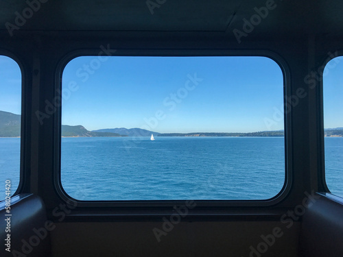 Sailboat sailing on river against clear sky seen through ferry window