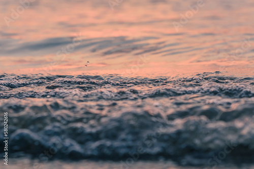 Close-up of waves on shore against cloudy sky during sunset photo