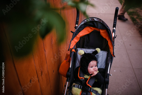 High angle view of cute newborn wearing bee costume in baby stroller on footpath during Halloween photo