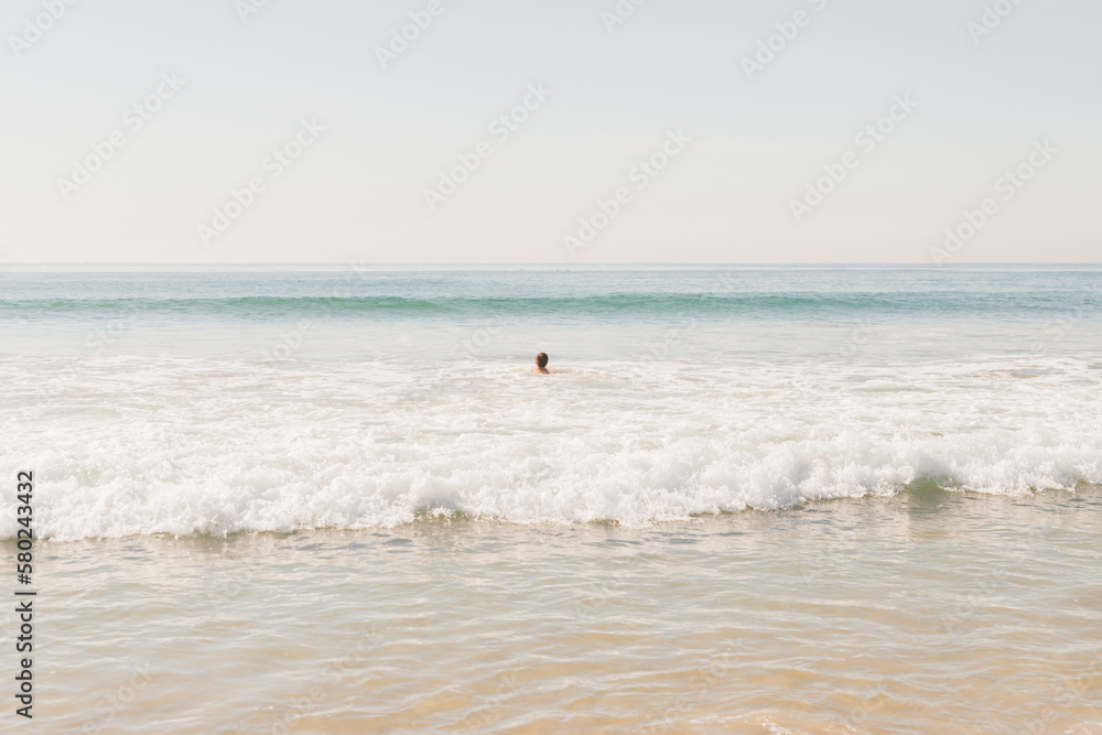Mid distance view of boy swimming in sea against clear sky Mid distance view of boy swimming in sea against clear sky