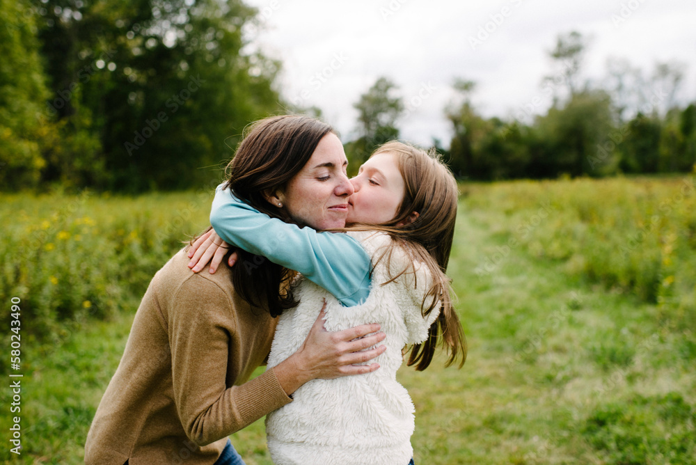 Daughter kissing mother while standing at park during winter Daughter kissing mother while standing at park during winter