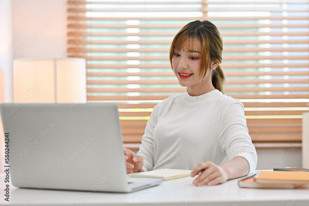 Attractive young creative woman working on design project, using laptop computer at home office. Attractive young creative woman working on design project, using laptop computer at home office.