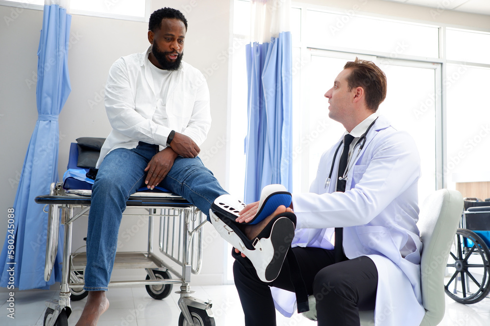 Male doctor treating foot injury patient. Male doctor treating foot injury patient.