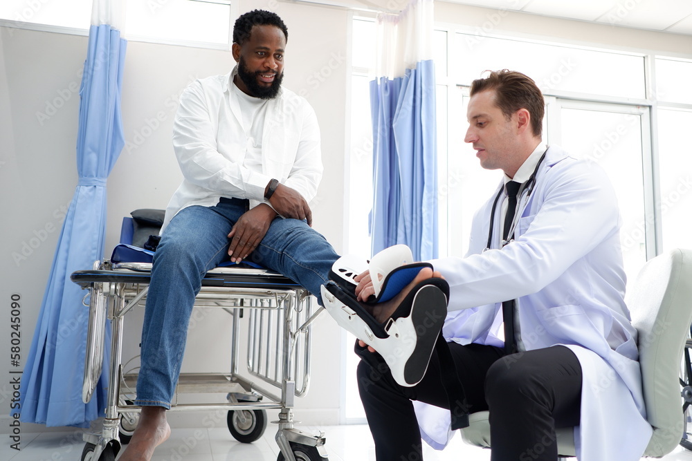 Fototapeta premium Male doctor treating foot injury patient.