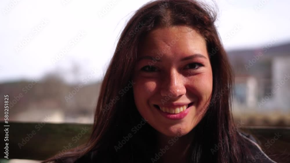 Happy young smiling woman with freckles outdoors portrait. Soft sunny colors. Outdoor close-up portrait of a young brunette woman and looking to the camera, posing against autumn nature background Happy young smiling woman with freckles outdoors portrait. Soft sunny colors. Outdoor close-up portrait of a young brunette woman and looking to the camera, posing against autumn nature background