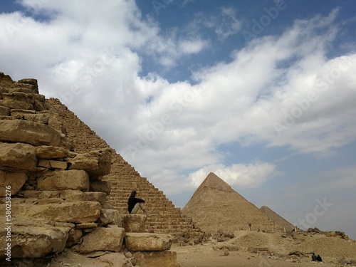 Stylish woman against the background of the Giza pyramid complex. Clear  sunny day  blue sky. Vacation and travel concept