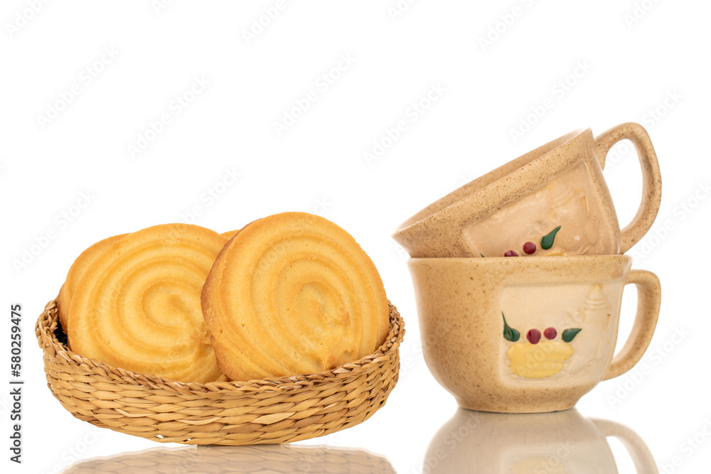 A few sweet cookies on a straw plate with two ceramic cups, macro, isolated on white background. A few sweet cookies on a straw plate with two ceramic cups, macro, isolated on white background.