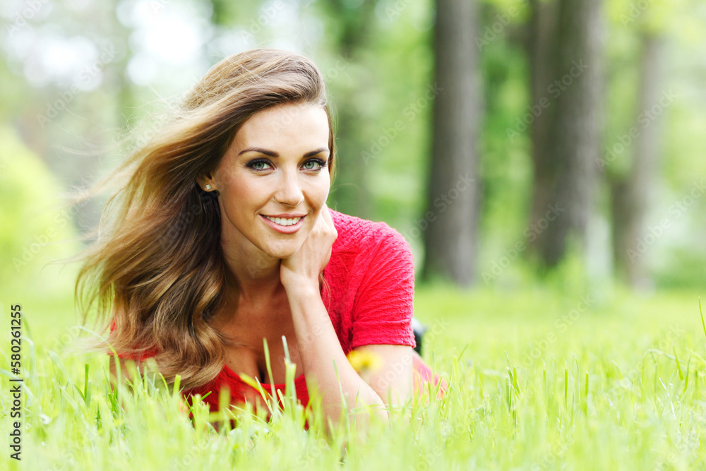 young woman in red dress lying on grass young woman in red dress lying on grass