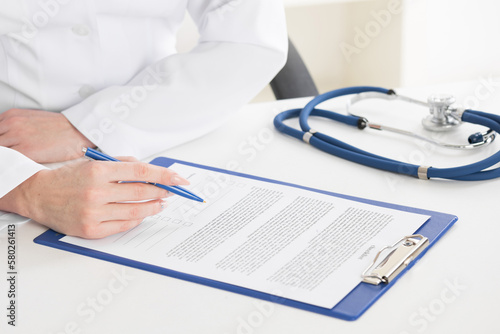 Doctor writing on sheet in clipboard