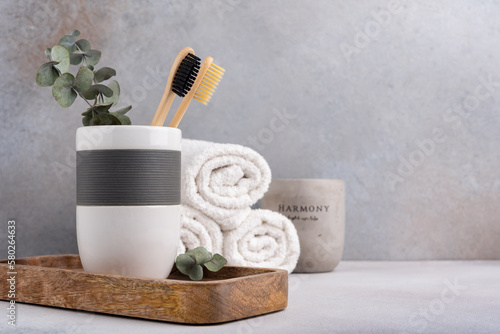 Eco friendly bathroom concept. Bamboo toothbrush in a glass with candle and towels