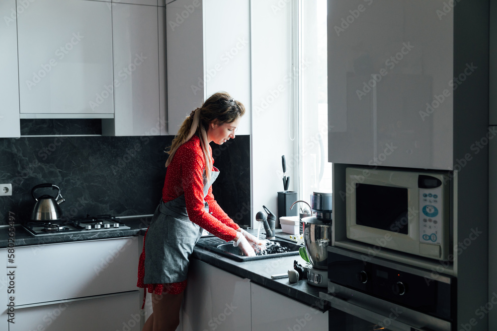 a woman washes dishes in the sink in the kitchen a woman washes dishes in the sink in the kitchen