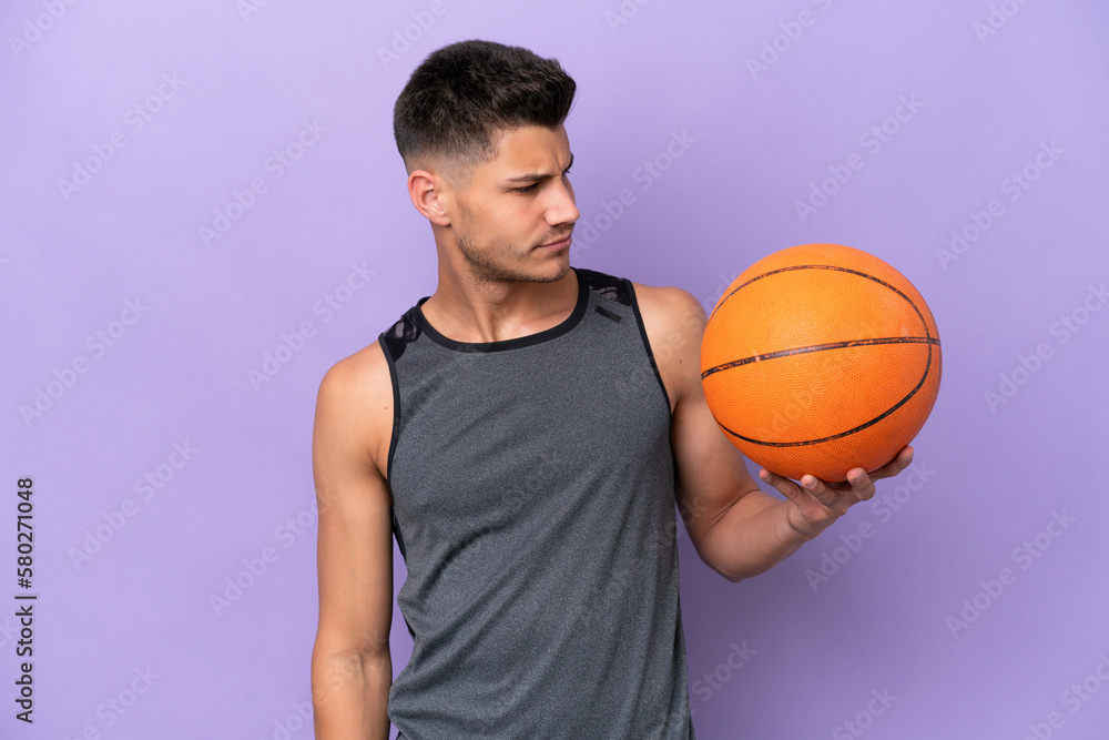 young caucasian woman  basketball player man isolated on purple background looking to the side