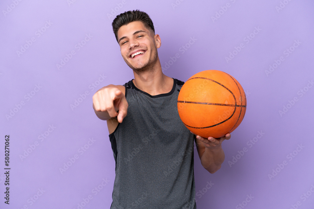 young caucasian woman  basketball player man isolated on purple background pointing front with happy expression