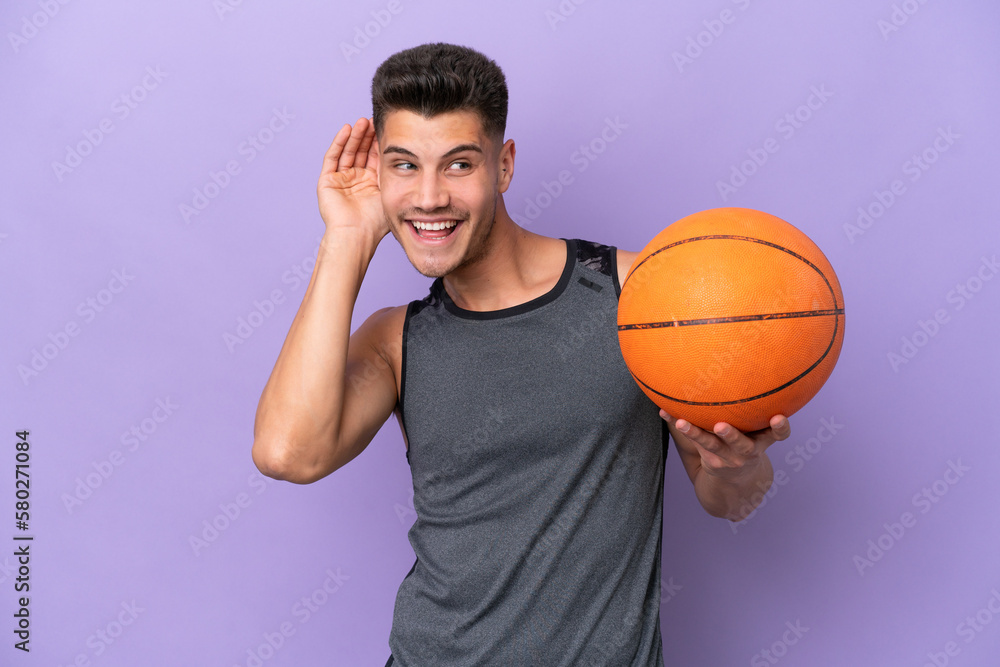 young caucasian woman  basketball player man isolated on purple background listening to something by putting hand on the ear