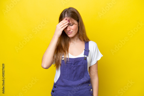 Young caucasian woman isolated on yellow background with headache