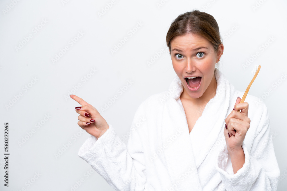 Young caucasian woman brushing teeth isolated on white background surprised and pointing finger to the side Young caucasian woman brushing teeth isolated on white background surprised and pointing finger to the side