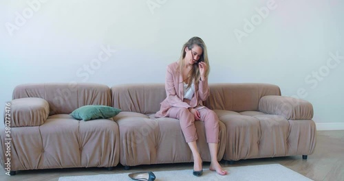 Young woman sits on a sofa in the living room and falls down after a overworking. She wants to get away from it all.