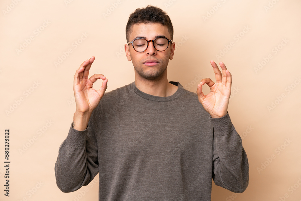 Fototapeta premium Young Brazilian man isolated on beige background in zen pose