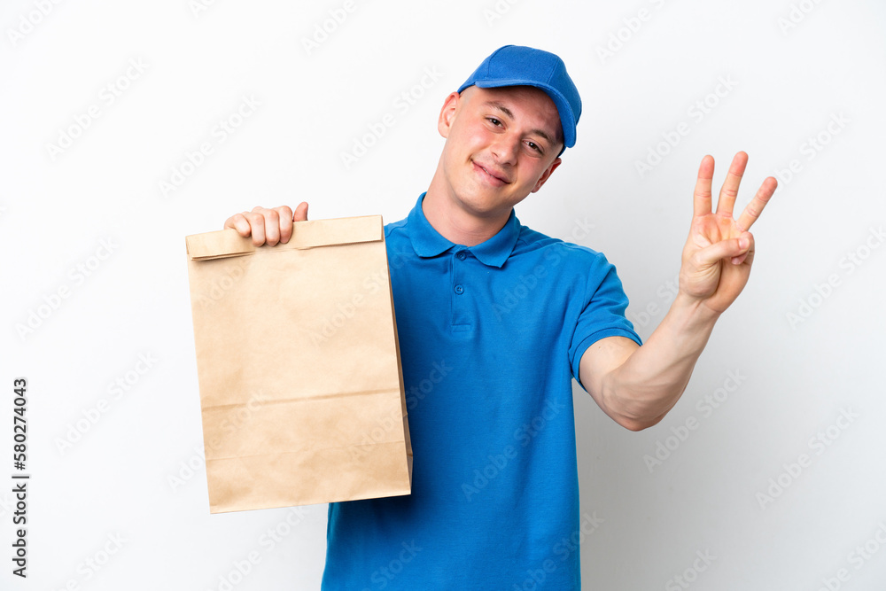Young Brazilian man taking a bag of takeaway food isolated on white background happy and counting three with fingers Young Brazilian man taking a bag of takeaway food isolated on white background happy and counting three with fingers