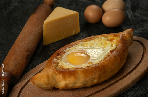 . Caucasian flatbread adjarian khachapuri with egg on a dark wooden . Adjarian Khachapuri Georgian cheese bread