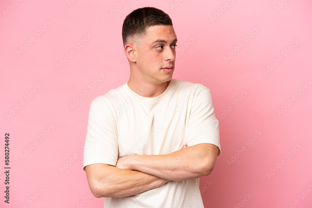 Obraz premium Young Brazilian man isolated on pink background keeping the arms crossed