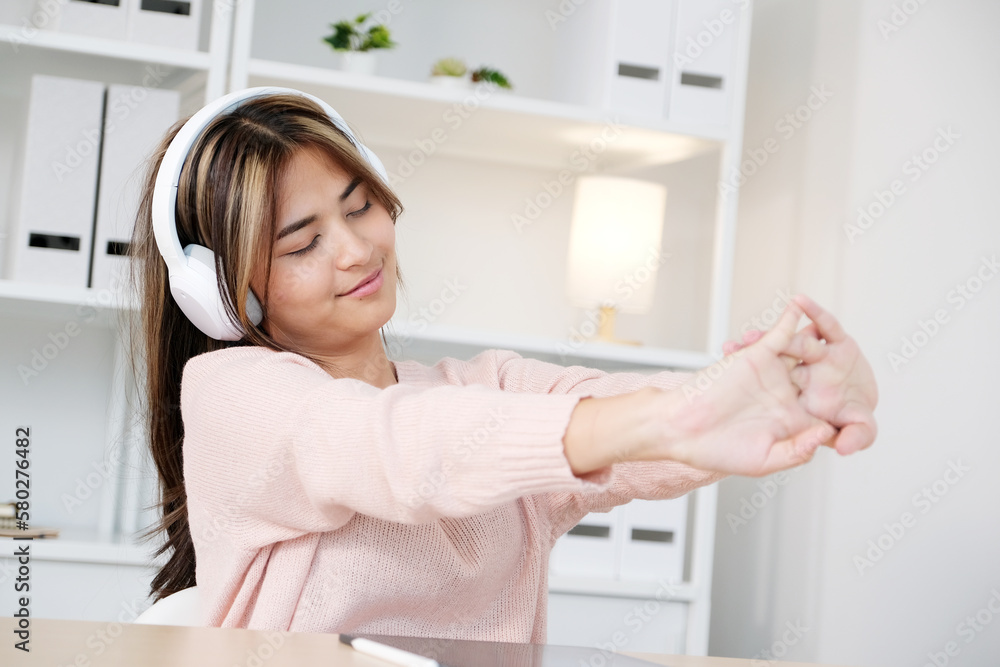 Young asian woman with headphones stretching for relax after working Young asian woman with headphones stretching for relax after working