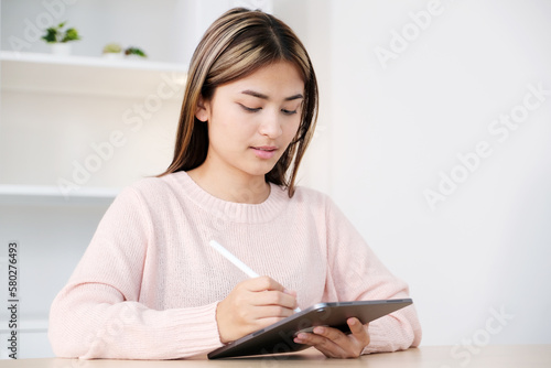 Young asian woman using digital tablet at home office