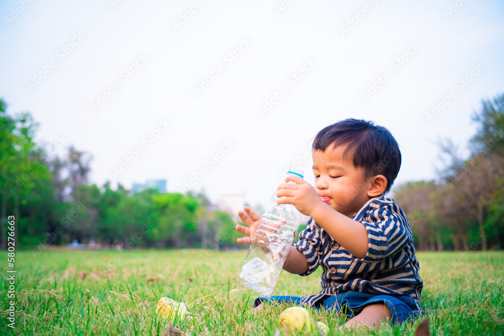 Toddler baby boy lying on green grass field holding water bottle Toddler baby boy lying on green grass field holding water bottle