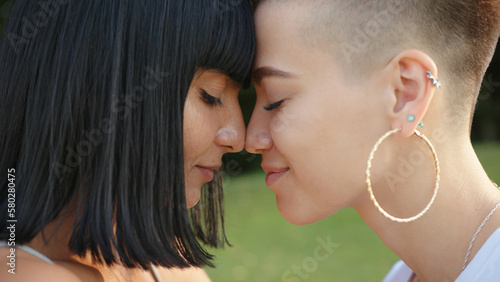 Close up portrait of kissing happy lesbian LGBT women in the park