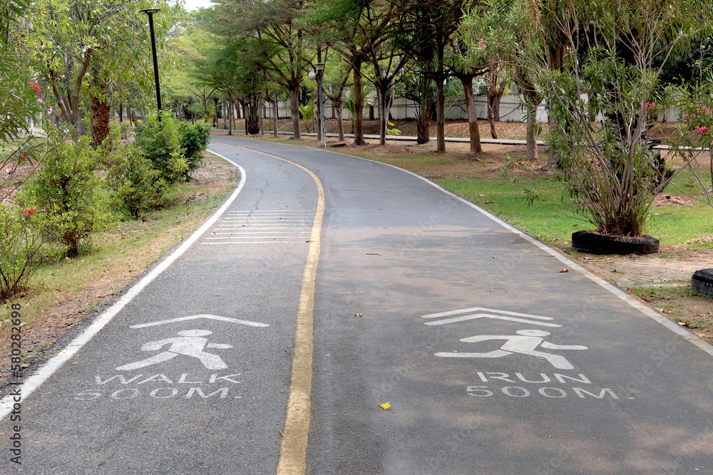 Road pathway in the park for relaxing walking jogging or ride bicycle and exercise at Cityscape of building from a Benjakiti park, Bangkok Thailand. Road pathway in the park for relaxing walking jogging or ride bicycle and exercise at Cityscape of building from a Benjakiti park, Bangkok Thailand.