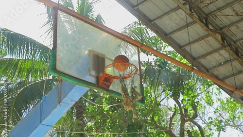 A young man scores in a basketball hoop, in a shed in the middle of nowhere, in the Philippines