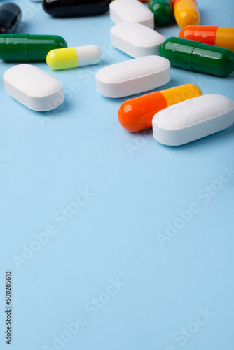 Front view of different pills on blue background,vertical banner with negative space.
