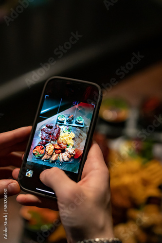 man hand with smartphone photographing food at restaurant or cafe