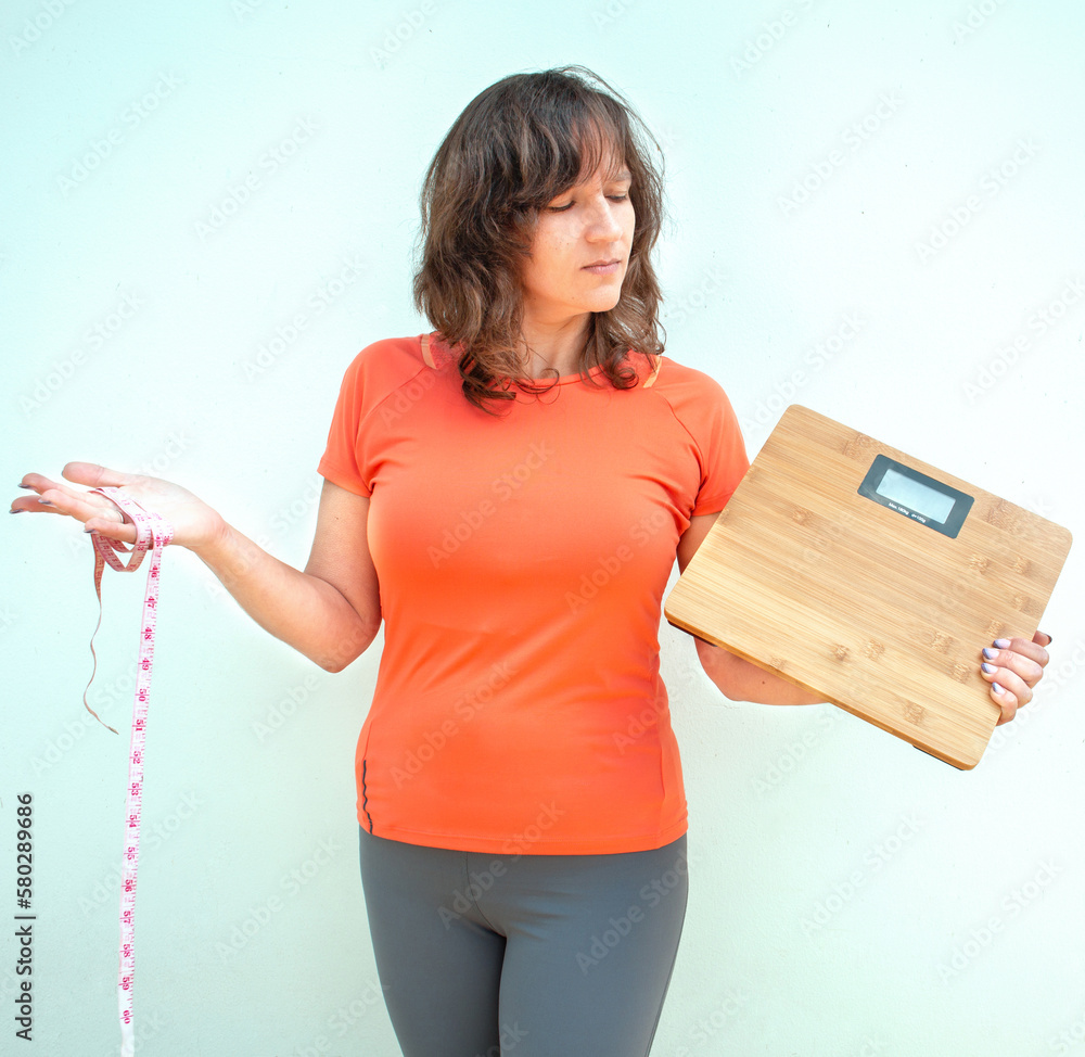 Woman holding measurement tape and weight scales