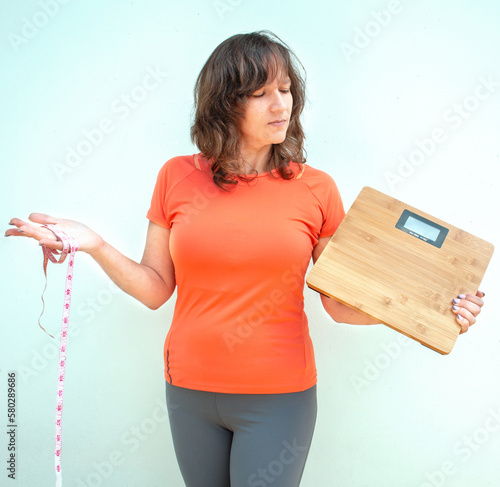 Obraz na płótnie Woman holding measurement tape and weight scales w salonie