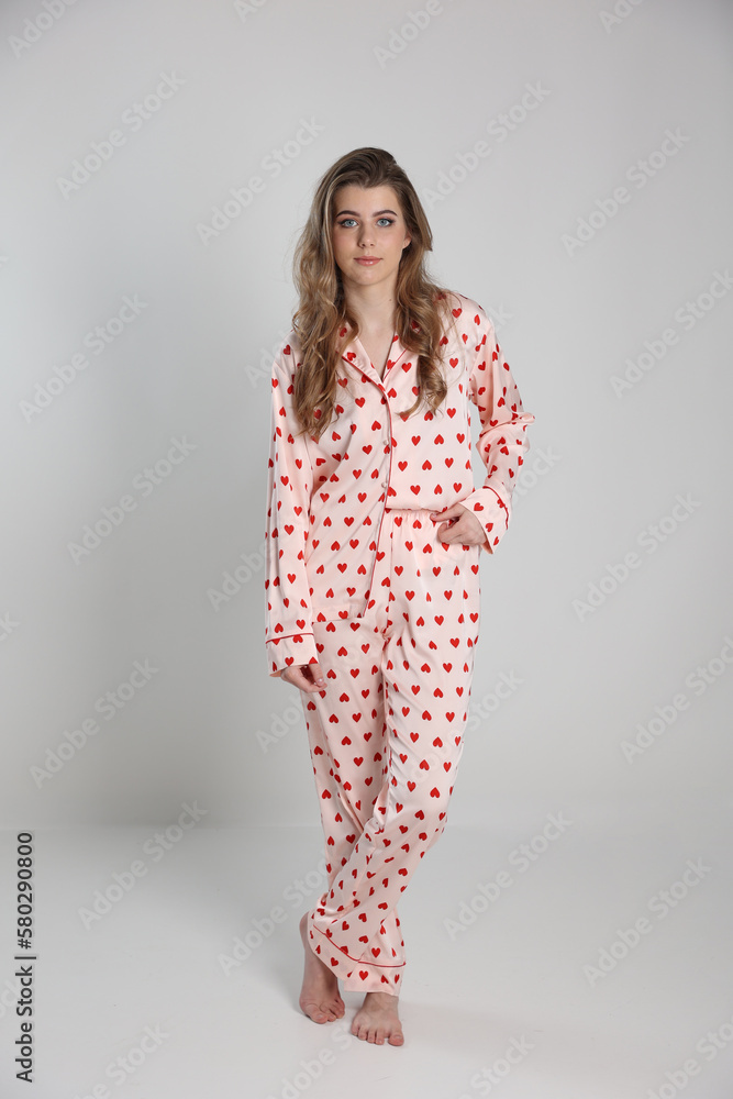 beautiful blonde girl on a white background in pajamas. pajamas with hearts. romantic pajamas. Valentine's Day. studio photo shoot in satin pajamas with a heart print. clothes for sleep and home beautiful blonde girl on a white background in pajamas. pajamas with hearts. romantic pajamas. Valentine's Day. studio photo shoot in satin pajamas with a heart print. clothes for sleep and home