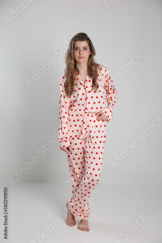 beautiful blonde girl on a white background in pajamas. pajamas with hearts. romantic pajamas. Valentine's Day. studio photo shoot in satin pajamas with a heart print. clothes for sleep and home