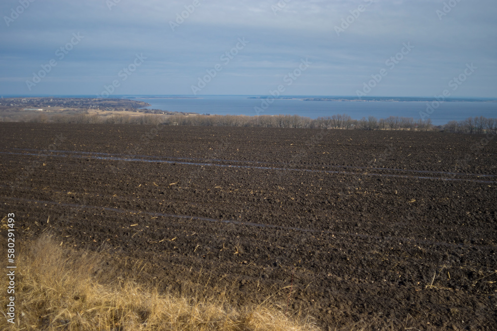 early spring landscape with agricultural field near Dnipro river down to  outskirts of Verkhnodniprovsk city, Ukraine
