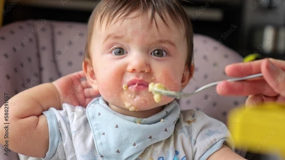 dirty baby eats porridge from a spoon. our dirty baby loves porridge and mess. happy family kindergarten kids concept. baby loves to eat porridge for breakfast. close-up baby dream eating porridge dirty baby eats porridge from a spoon. our dirty baby loves porridge and mess. happy family kindergarten kids concept. baby loves to eat porridge for breakfast. close-up baby dream eating porridge
