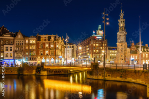 Amsterdam, Netherlands. Evening cityscape. Dark sky and city lights. Dutch canals. Reflections on the surface of the water. Photography for design and wallpaper.