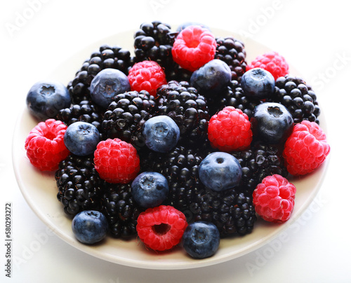 Blackberries, raspberry and blueberrys on white plate.