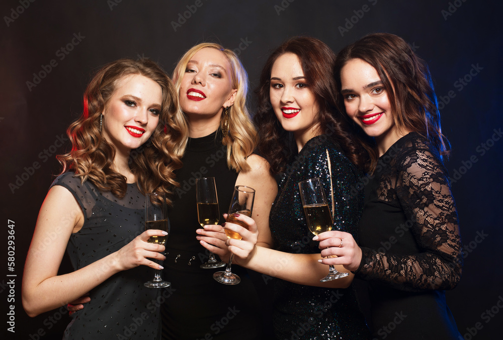 Young female friends clinking flutes with sparkling wine.