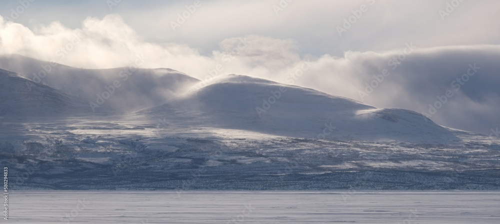 Beautiful scenery of snowy mountains in clouds. View from Lake Torneträsk (Tornestrask) around Abisko National Park (Abisko nationalpark). Sweden, Arctic Circle, Swedish Lapland
