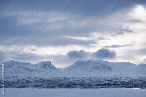 Winter mountain panorama with Lapporten (Lapponian Gate) or Tjuonavagge, U-shaped valley around Abisko National Park in Lapland, Sweden, Arctic Circle. View from lake Torneträsk (Tornestrask)
