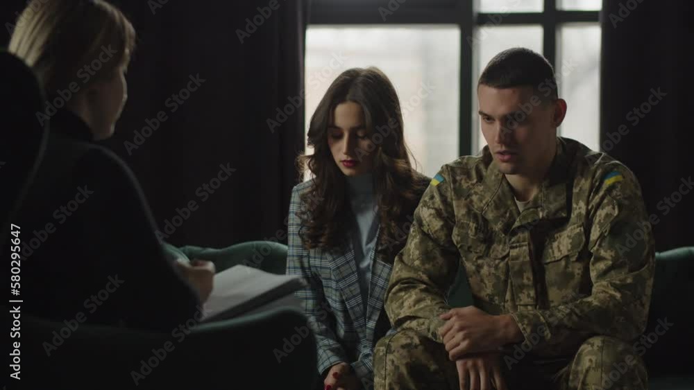 A Ukrainian soldier suffering from PTSD talks about negative memories to a military psychologist. A woman tries to morally support her husband during an appointment with a military psychologist. A Ukrainian soldier suffering from PTSD talks about negative memories to a military psychologist. A woman tries to morally support her husband during an appointment with a military psychologist.