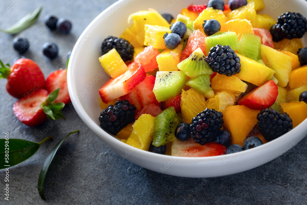 Bowl of healthy fresh summer mixed fruit salad close-up. Plate delicious and wholesome food with copy space