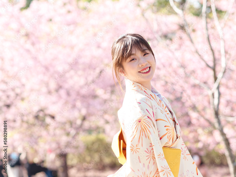 Portrait of beautiful young Chinese girl in Japanese kimono posing with blossom cherry flowers background in spring garden, beauty, emotion, lifestyle, expression and people concept. Portrait of beautiful young Chinese girl in Japanese kimono posing with blossom cherry flowers background in spring garden, beauty, emotion, lifestyle, expression and people concept.
