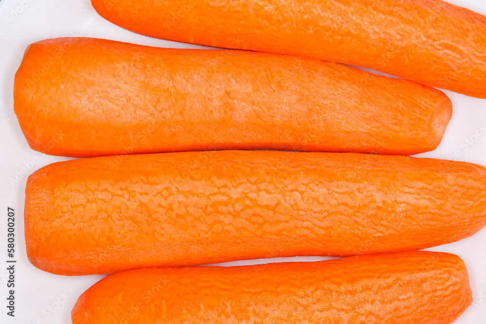 Fresh peeled carrots on white dish, top view close-up Fresh peeled carrots on white dish, top view close-up